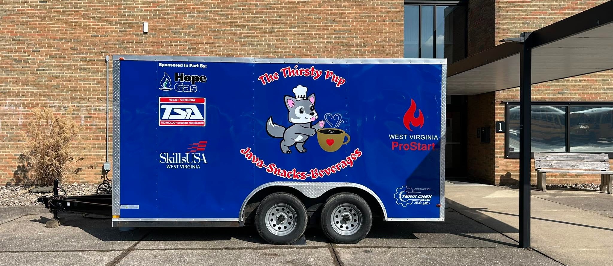 A blue trailer with a cartoon character on the side parked in front of a brick building.