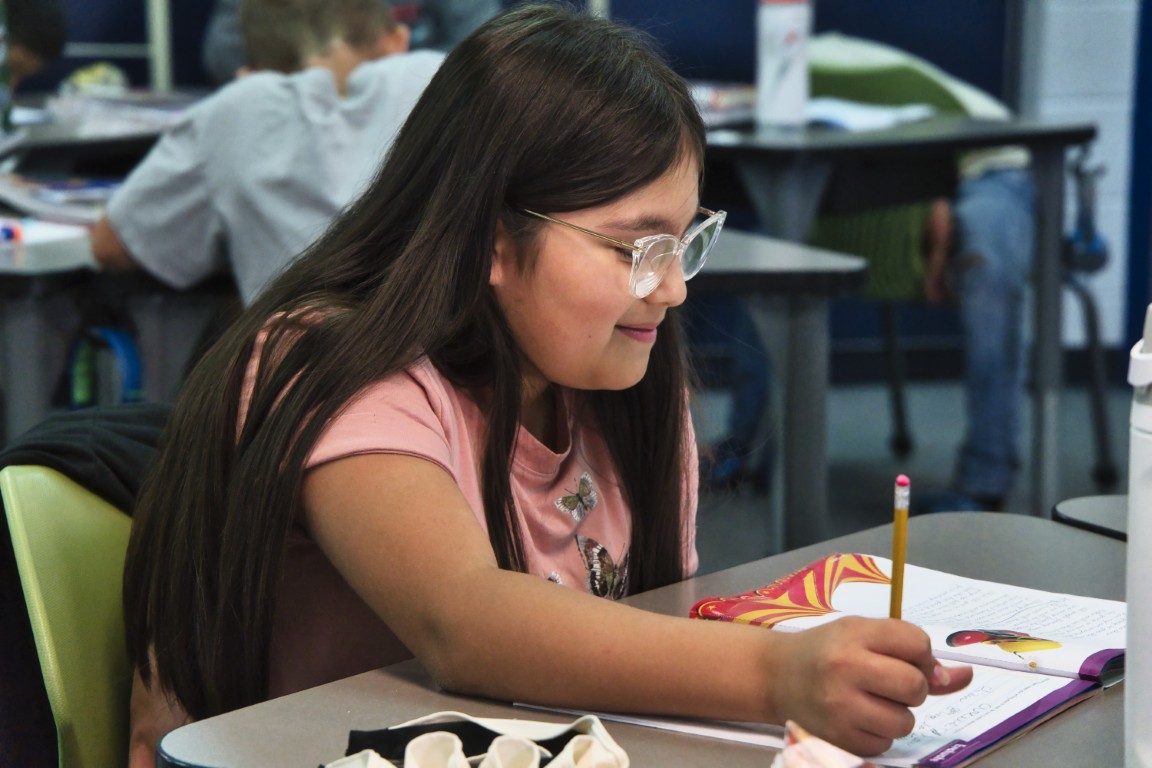 Student working on assignment at their desk with a pencil
