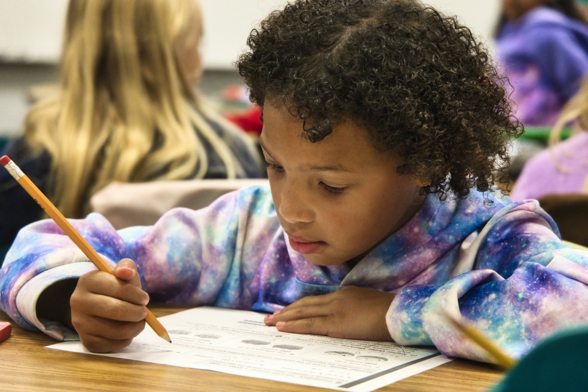 Student working on assignment with a pencil at their desk