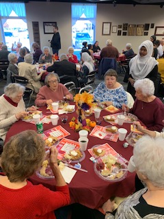 elderly people sitting with food on the table