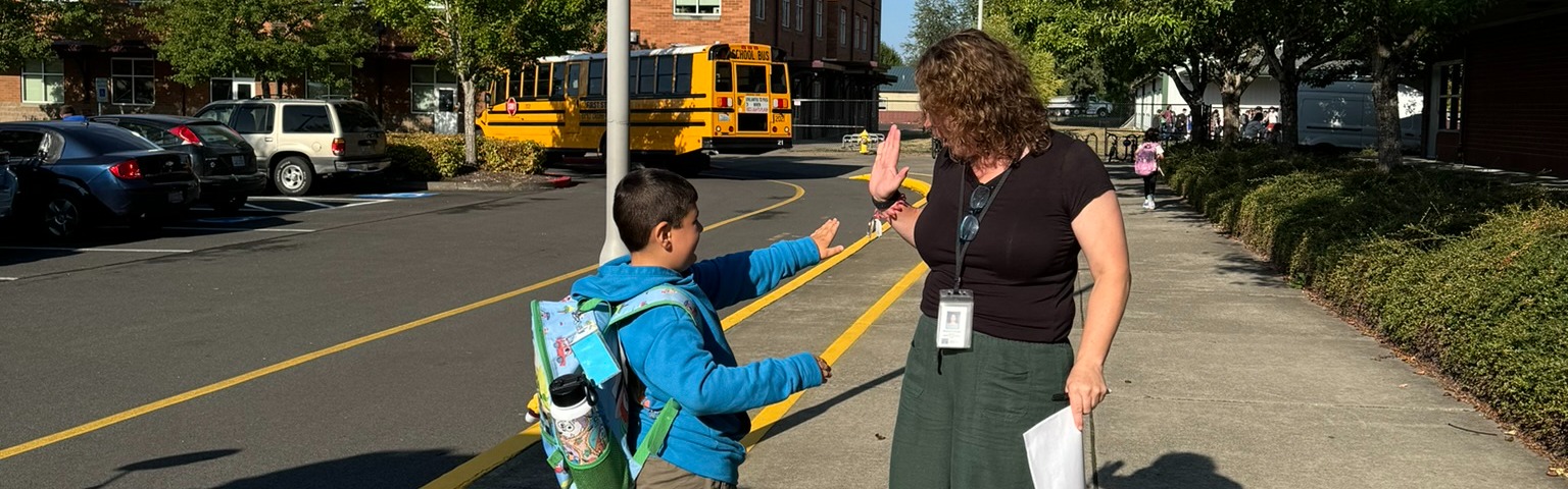 student high-fives a teacher outside