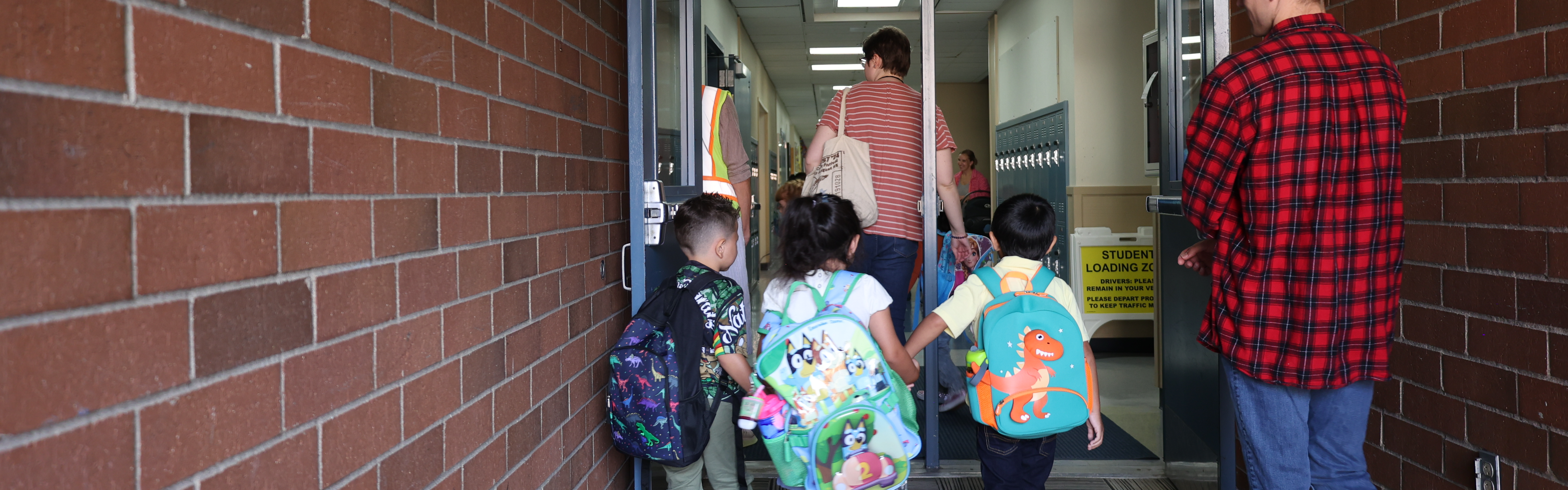 3 students walk hand in hand into the school building