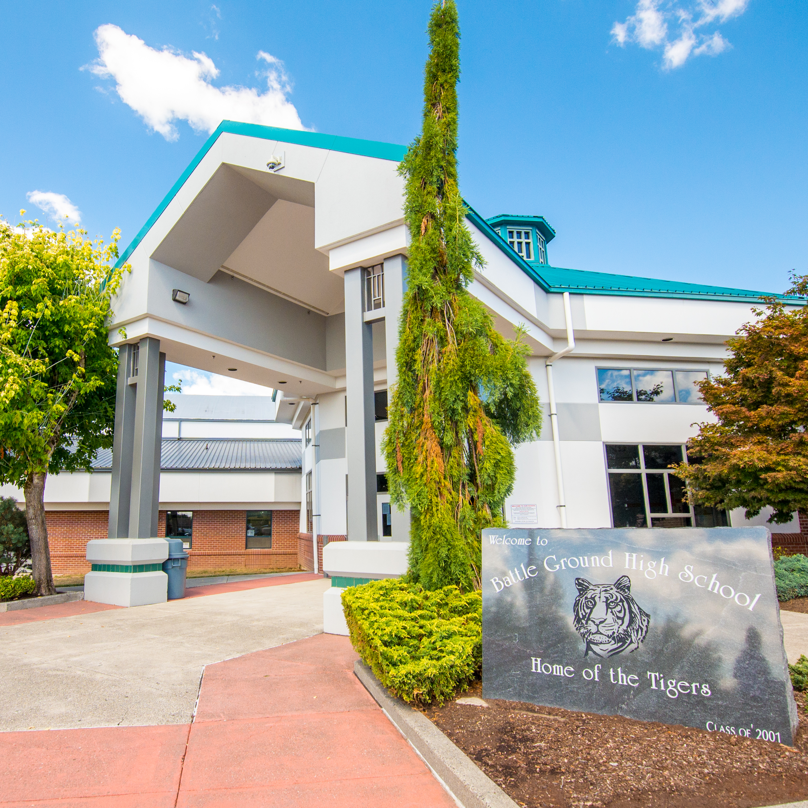 Exterior of Battle Ground High School with a sign in the foreground that reads, "Welcome to Battle Ground High School, Home of the Tigers"