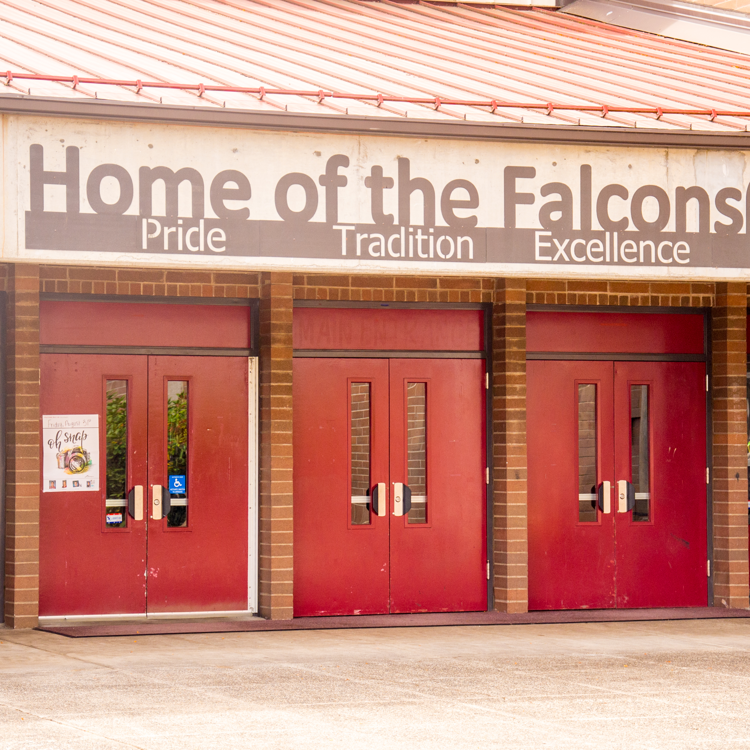 Exterior shot of the school's main entrance. Above it is a sign that reads, "Home of the Falcons: Pride, Tradition, Excellence"