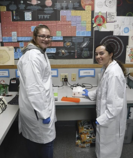 two students in the lab smiling at the camera