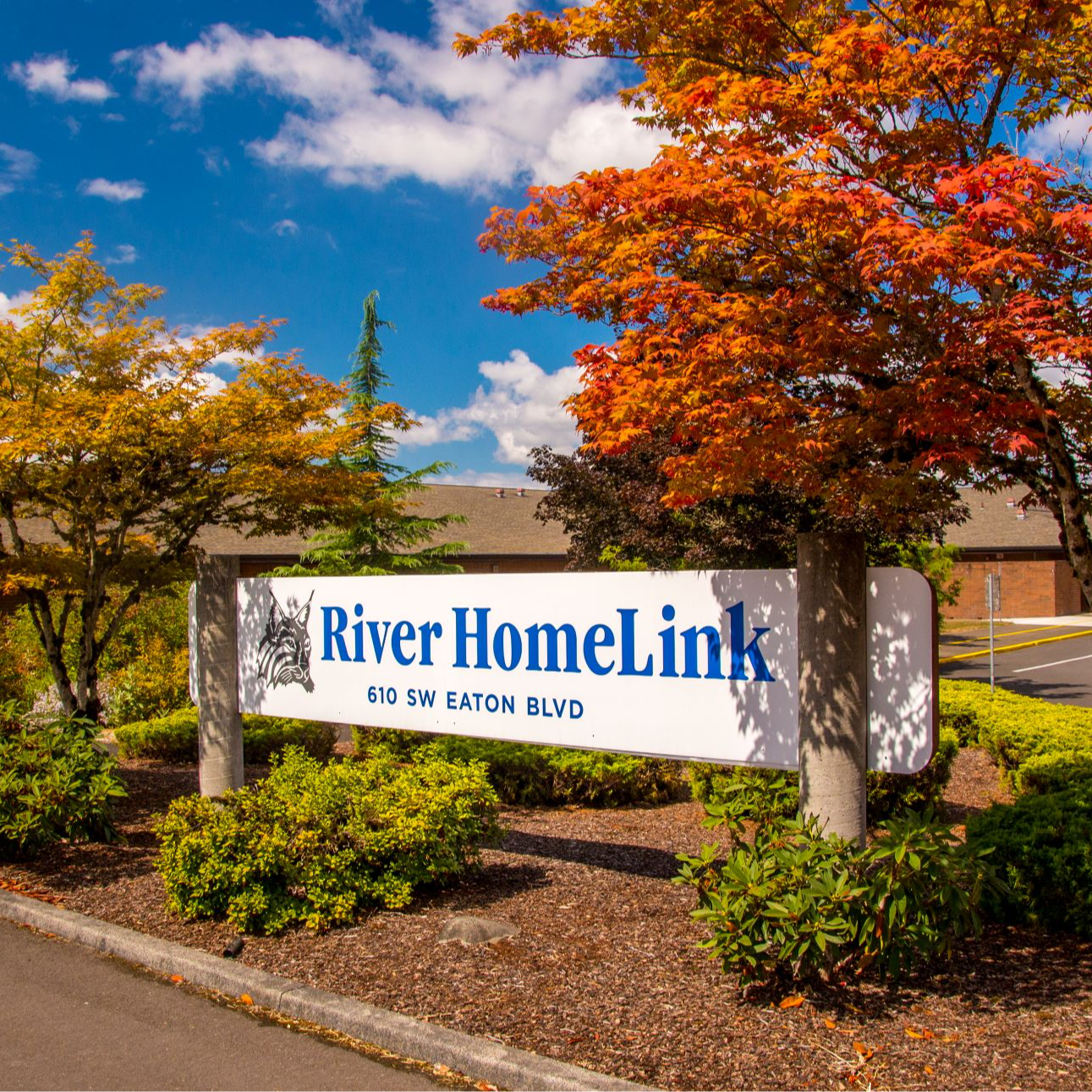 Exterior shot of River HomeLink, with sign in the foreground that says the school name and address