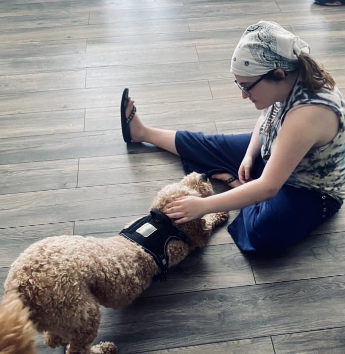 A woman sitting on the floor petting a dog.