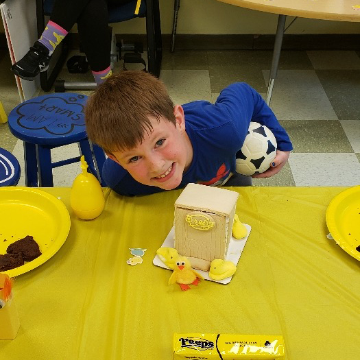 A young boy laying on a table in front of a cake