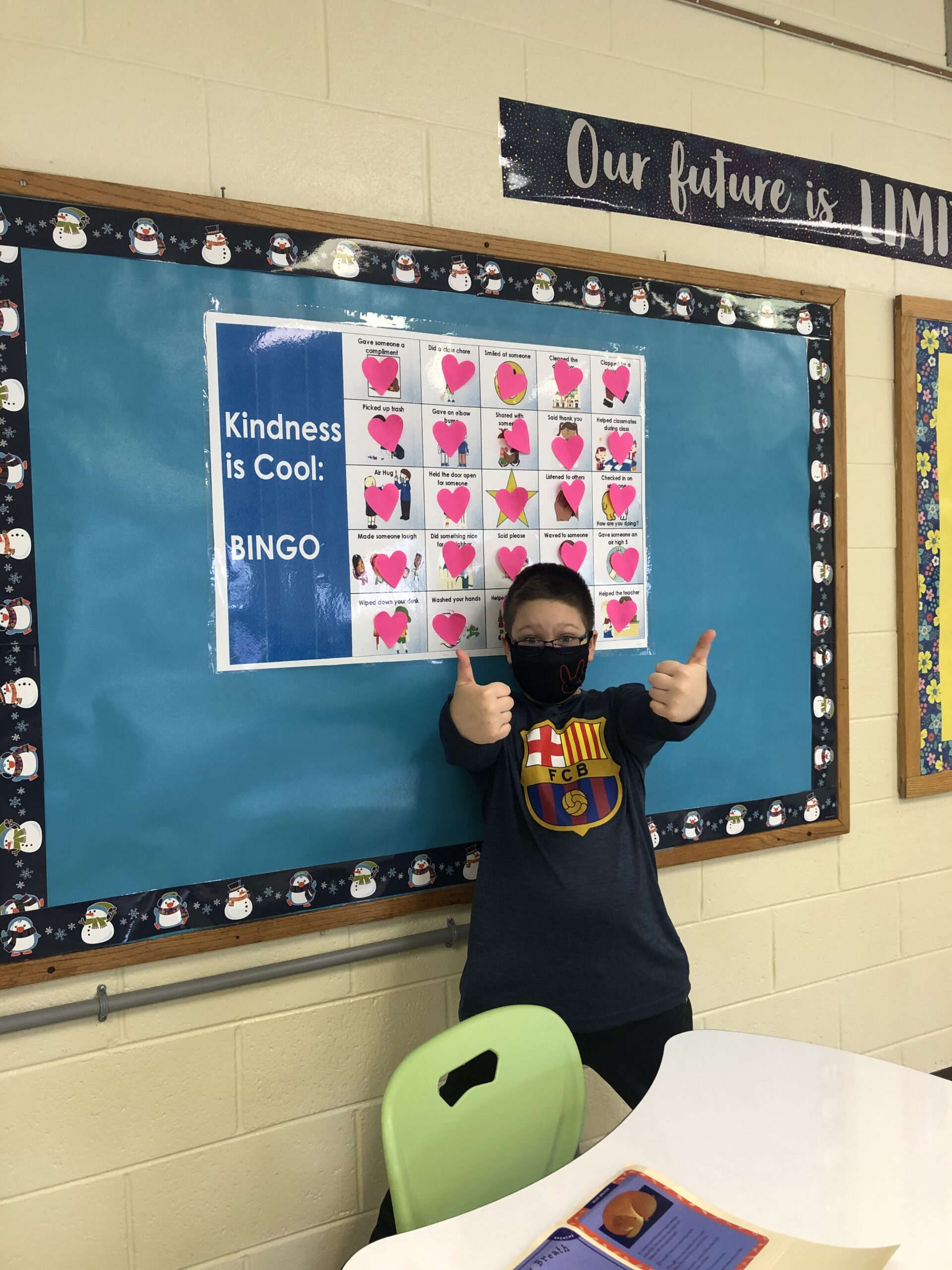 A young boy wearing a face mask in front of a blackboard