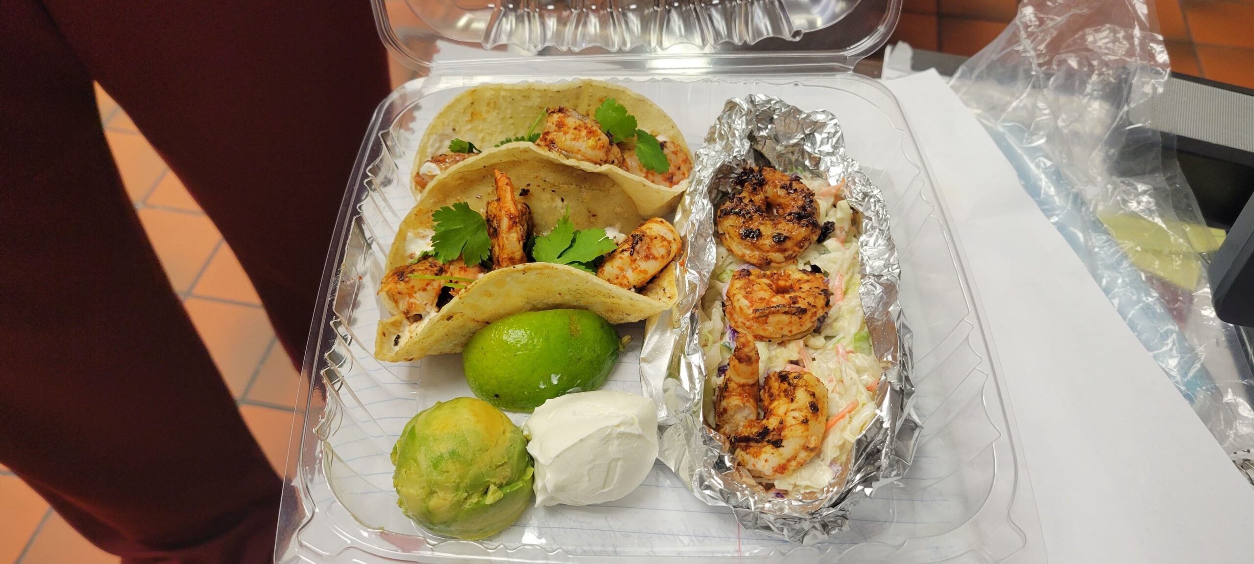 A plastic container with shrimp and a lime