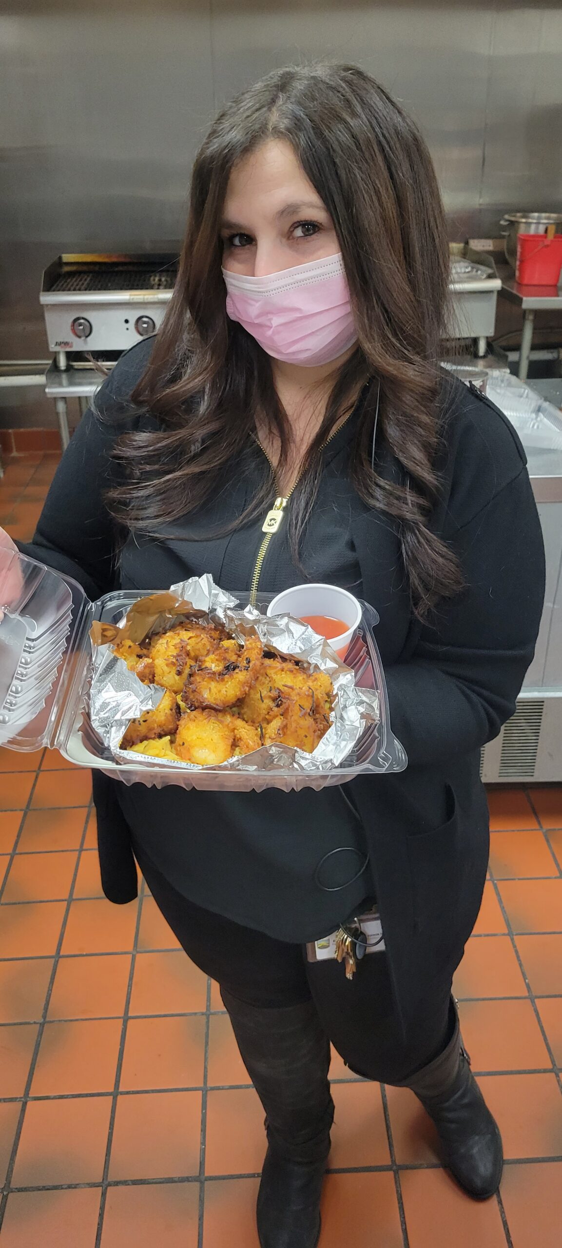 Woman in face mask holding food tray.