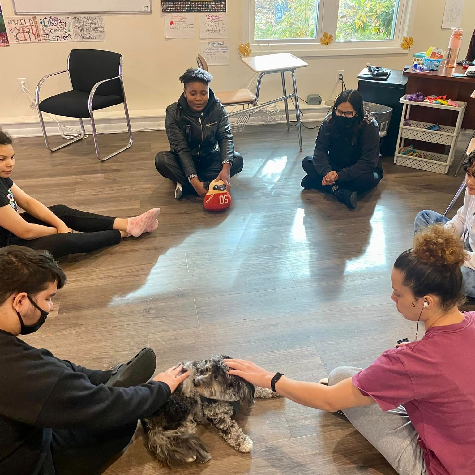 Students petting therapy dog while sitting on floor in circle