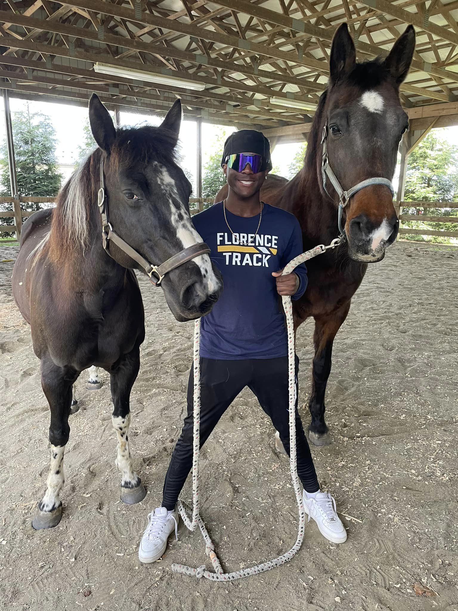 student posing with horses