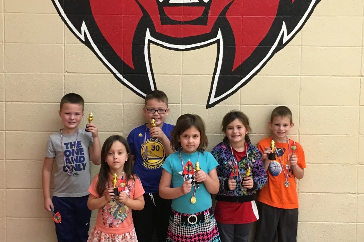 students holding small gold trophies