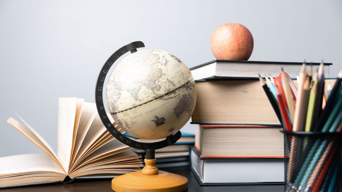 Globe, books, snakcs piled on a desk