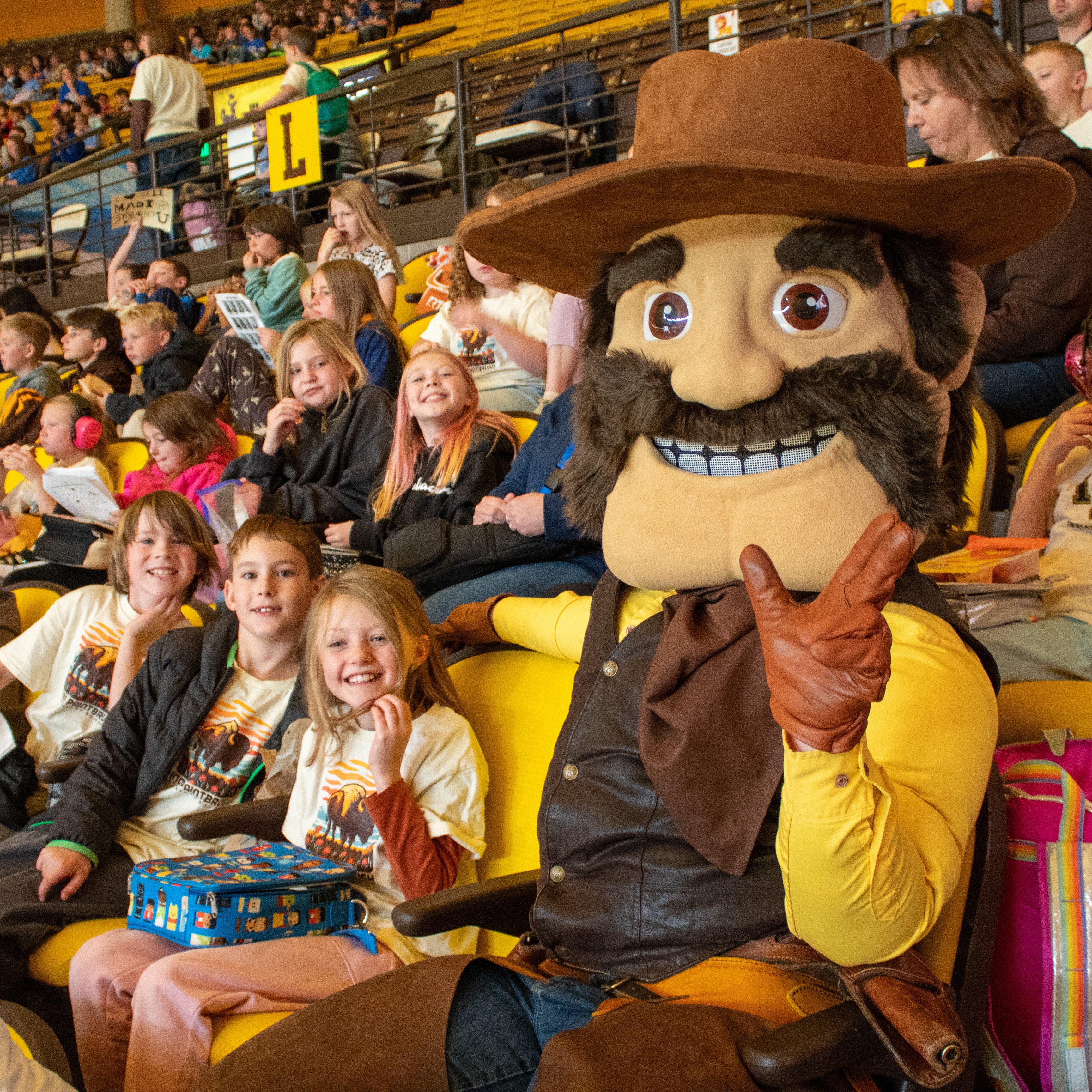 Young children cheering at a basketball game with team mascot