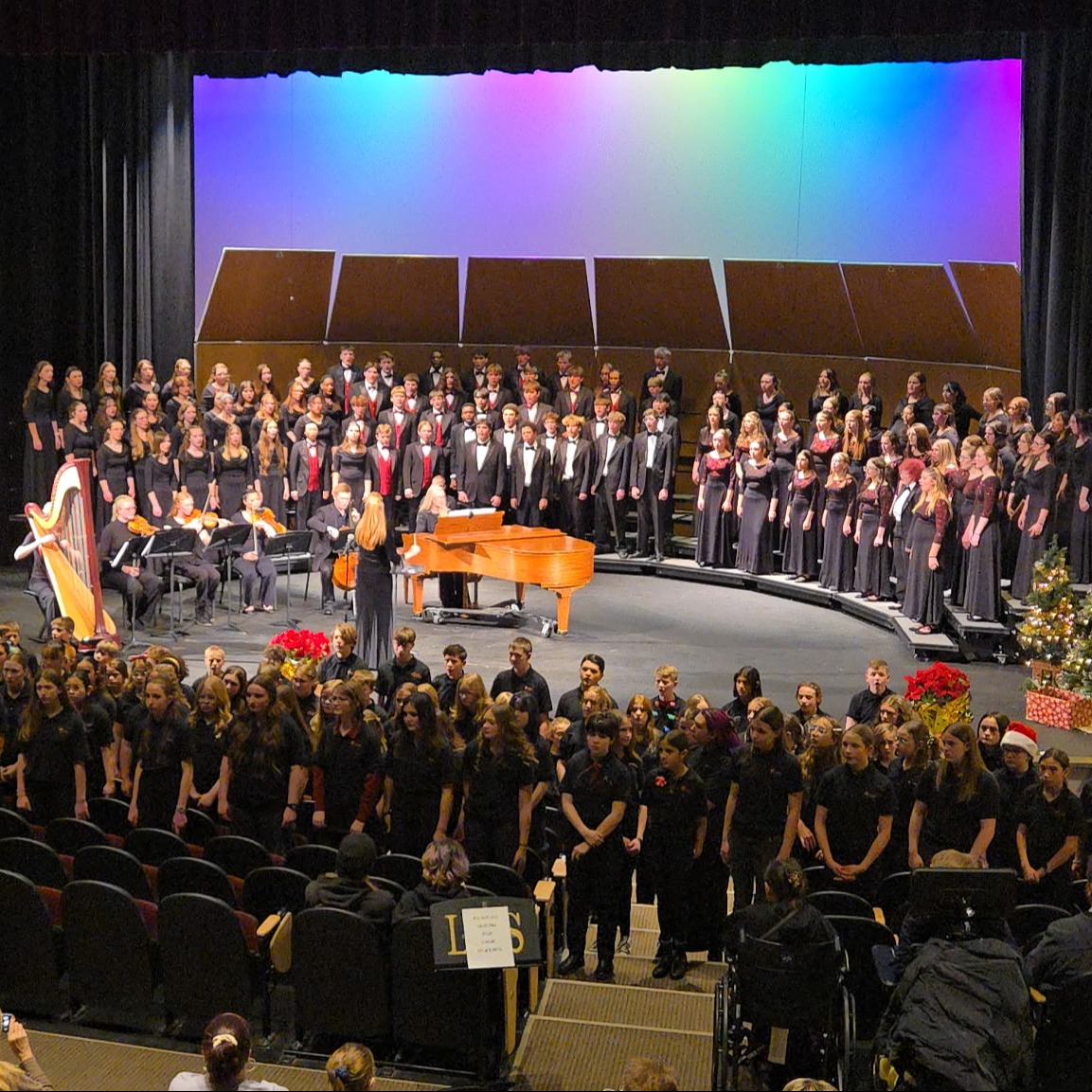 Students dressed in all black singing on stage and throughout the audience 