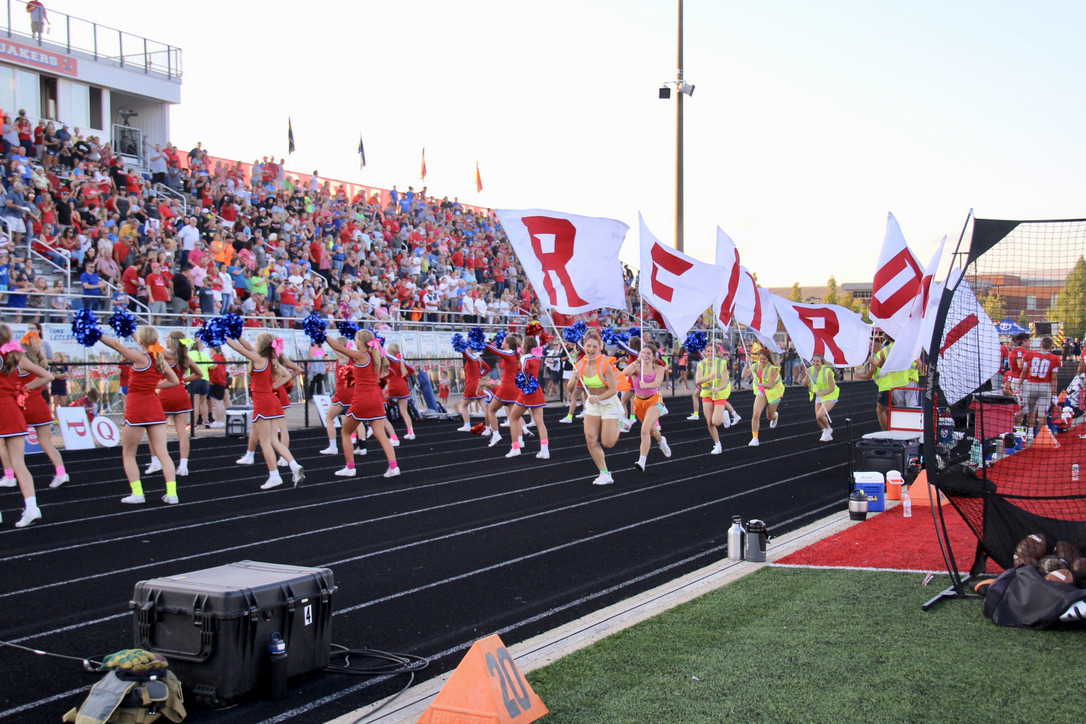 Students parade the Red Pride flags after the Quakers score a Homecoming touchdown