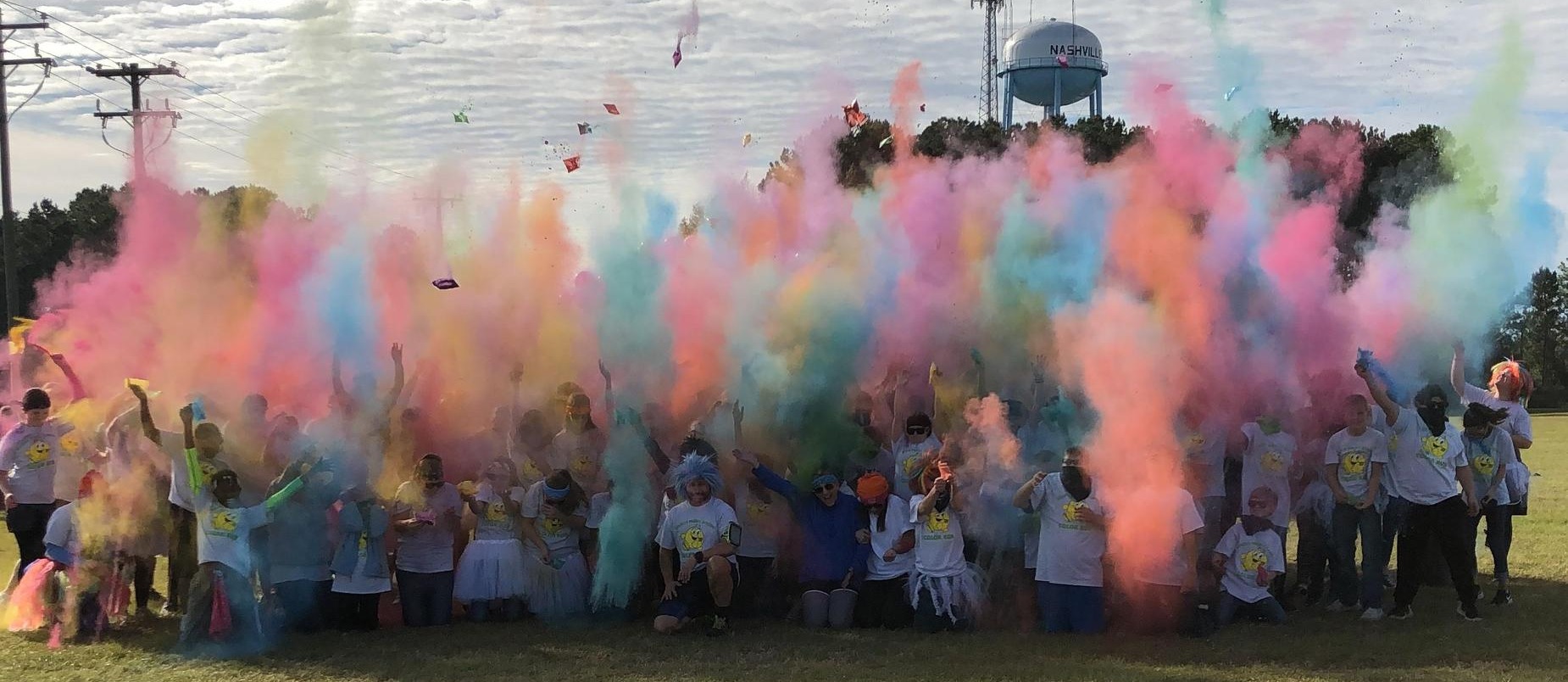group of students and staff with colored smoke power being thrown