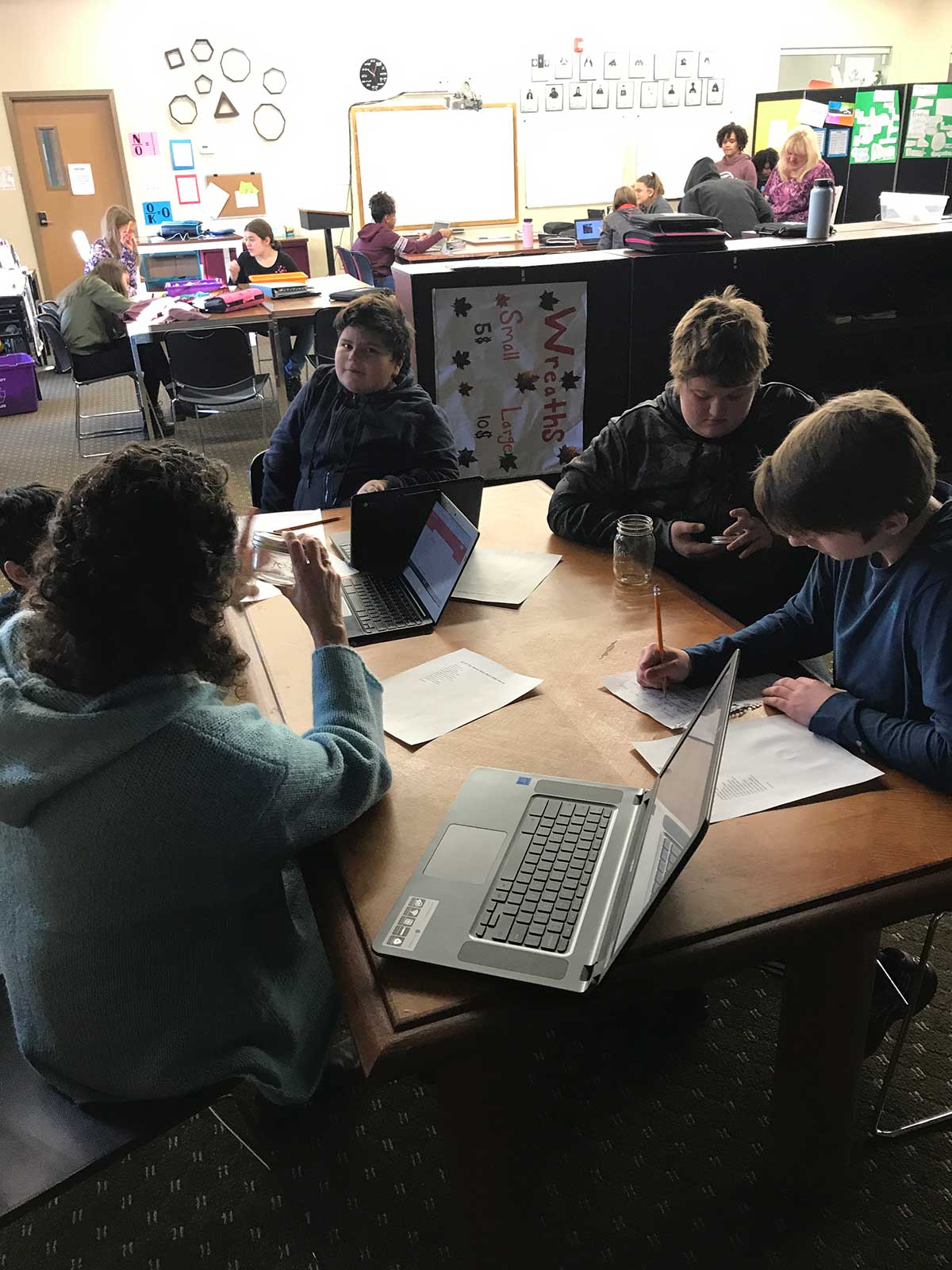 A diverse group of people sitting at a table with laptops, working together on a project.