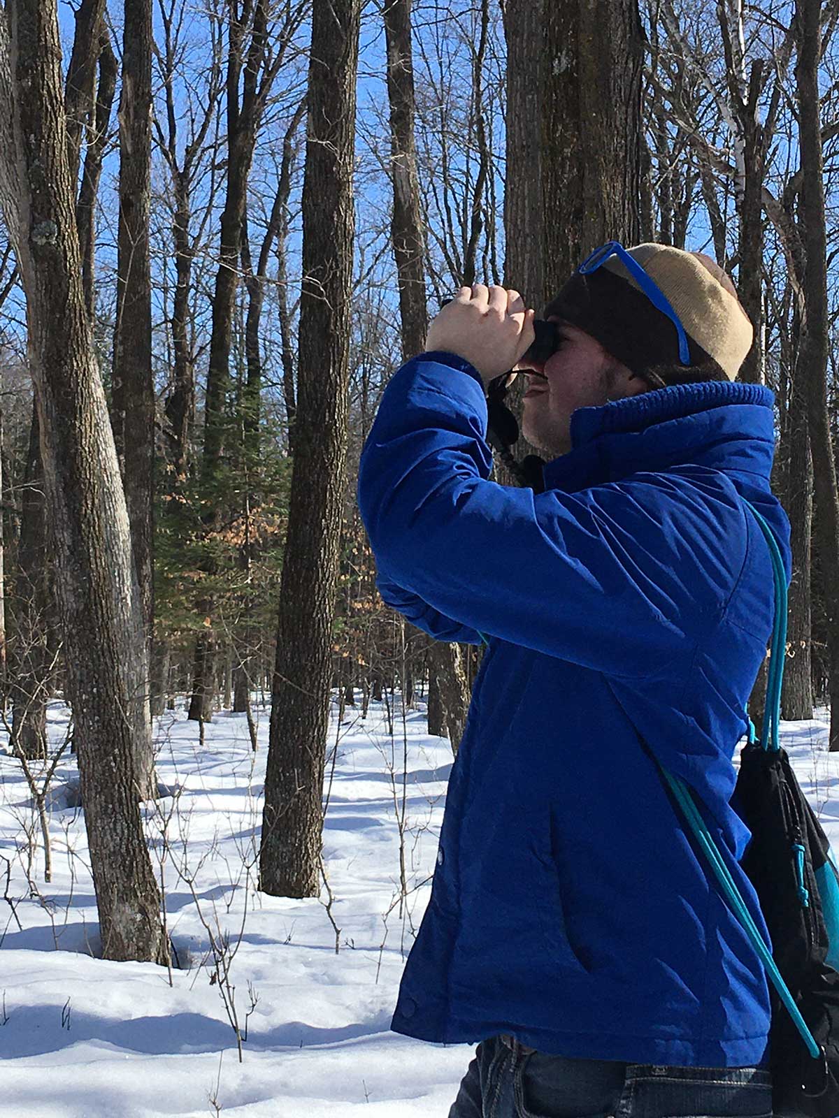 A man in a blue jacket and hat standing outdoors.