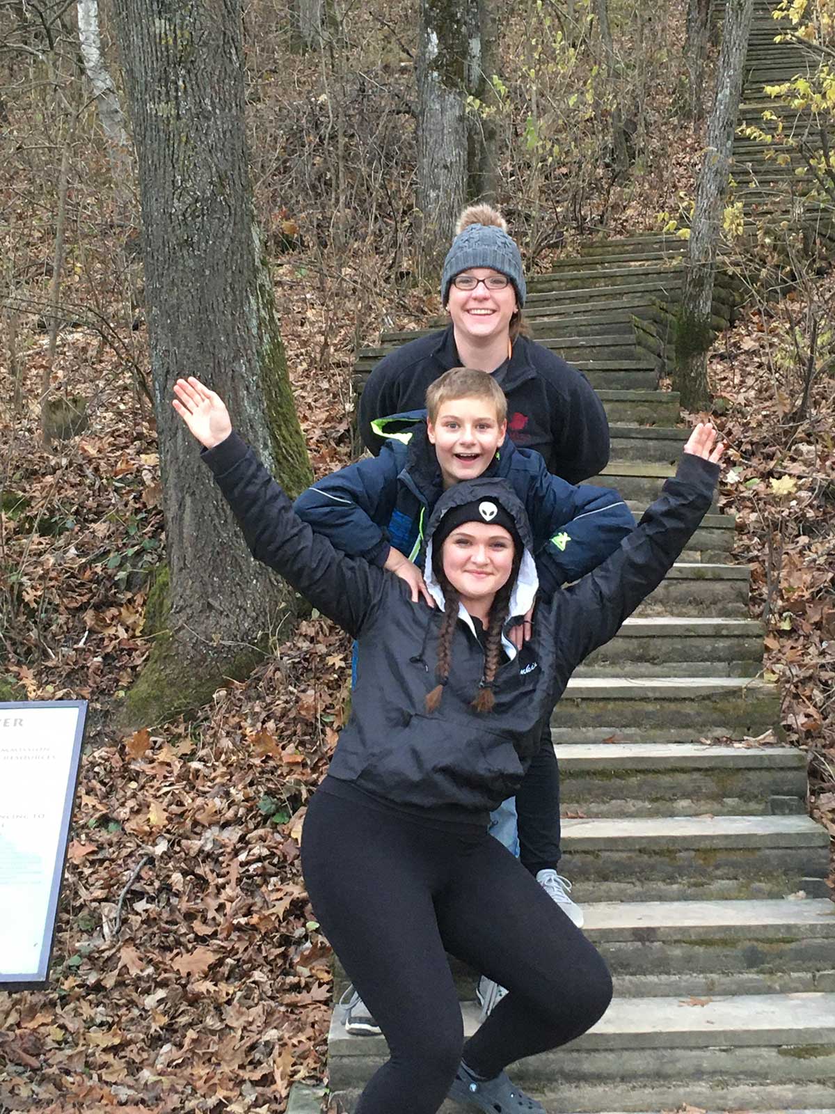 Three friends smiling for a photo on stairs.