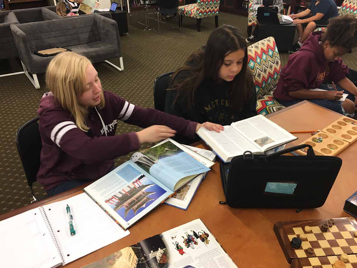 Two girls studying together in a library.