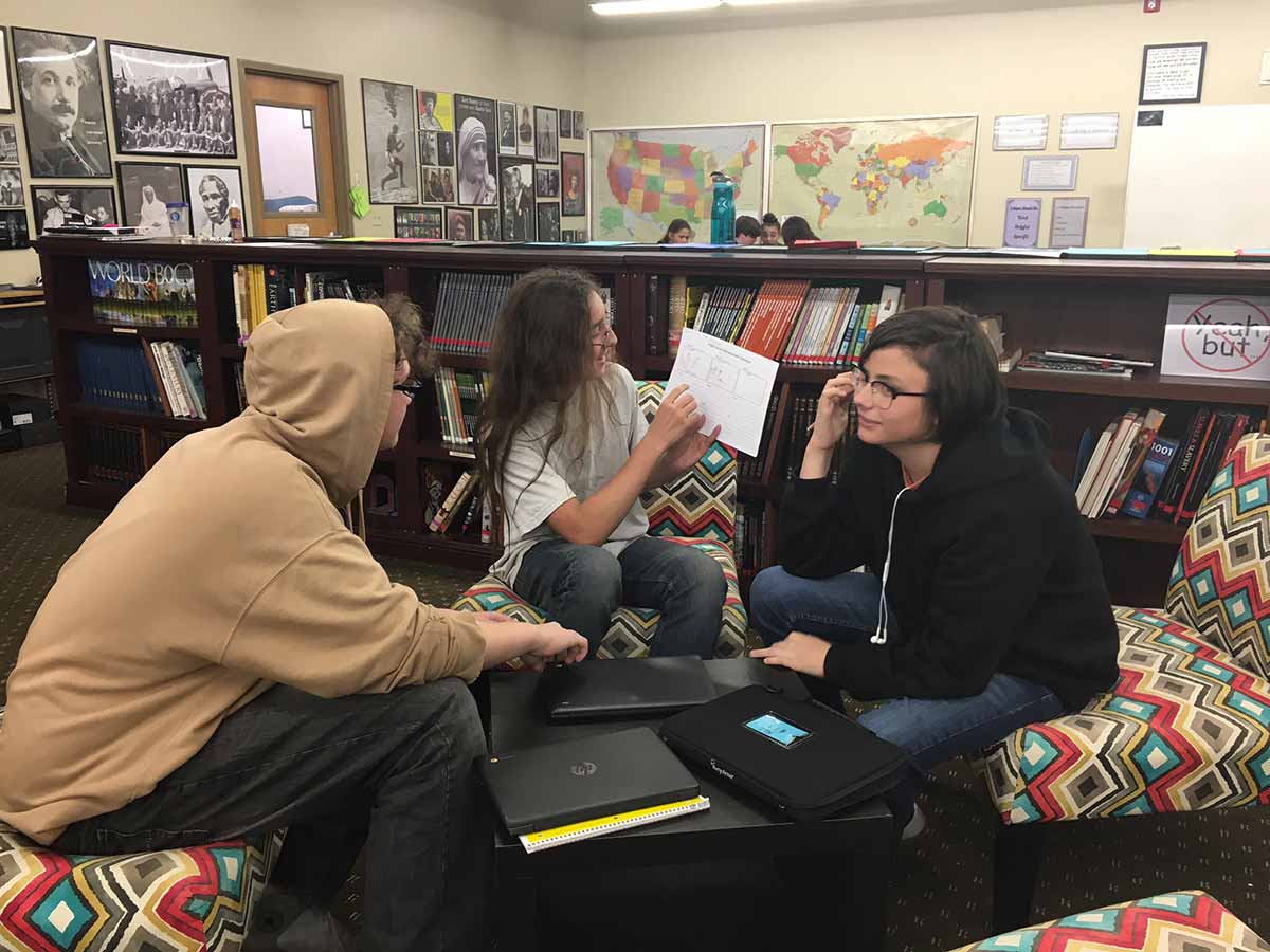Three people studying together at a library table.