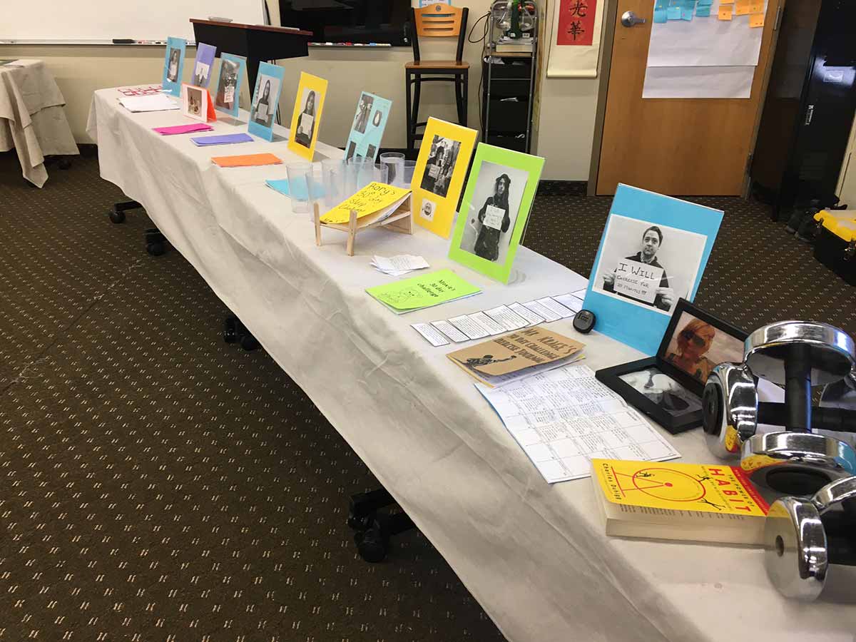 A cluttered table with various pictures and items scattered on top.