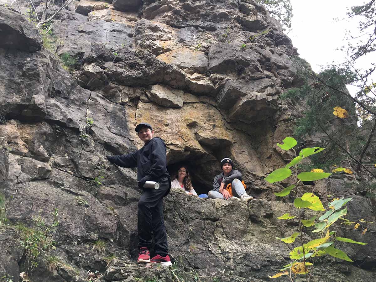 Three people standing on a rock in the woods, enjoying nature together.