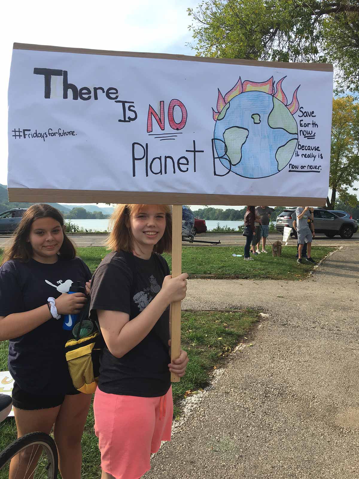 Two girls holding a sign that says "there is no planet B" at a climate change protest.