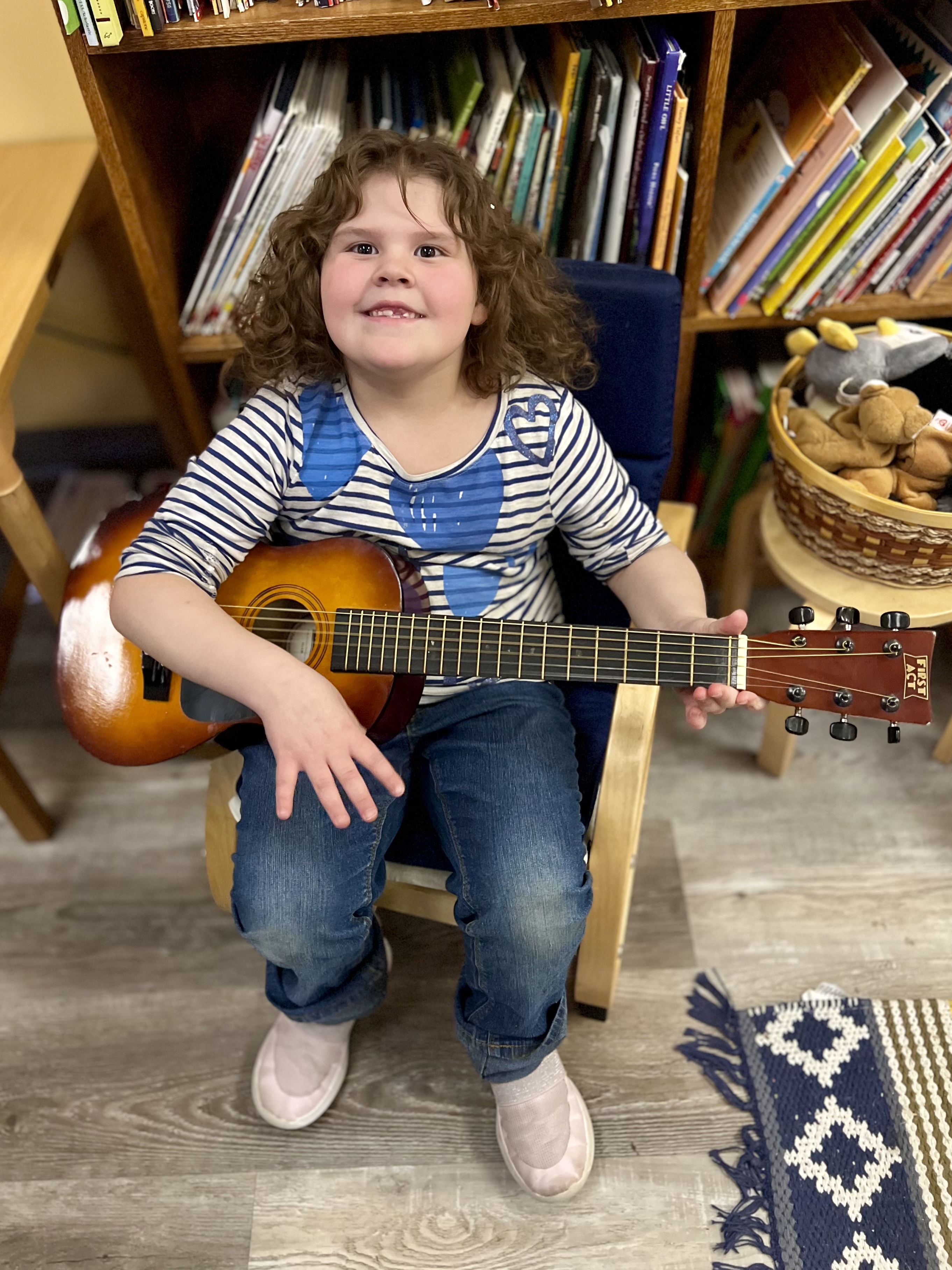 Children's House Student playing the guitar in the classroom.