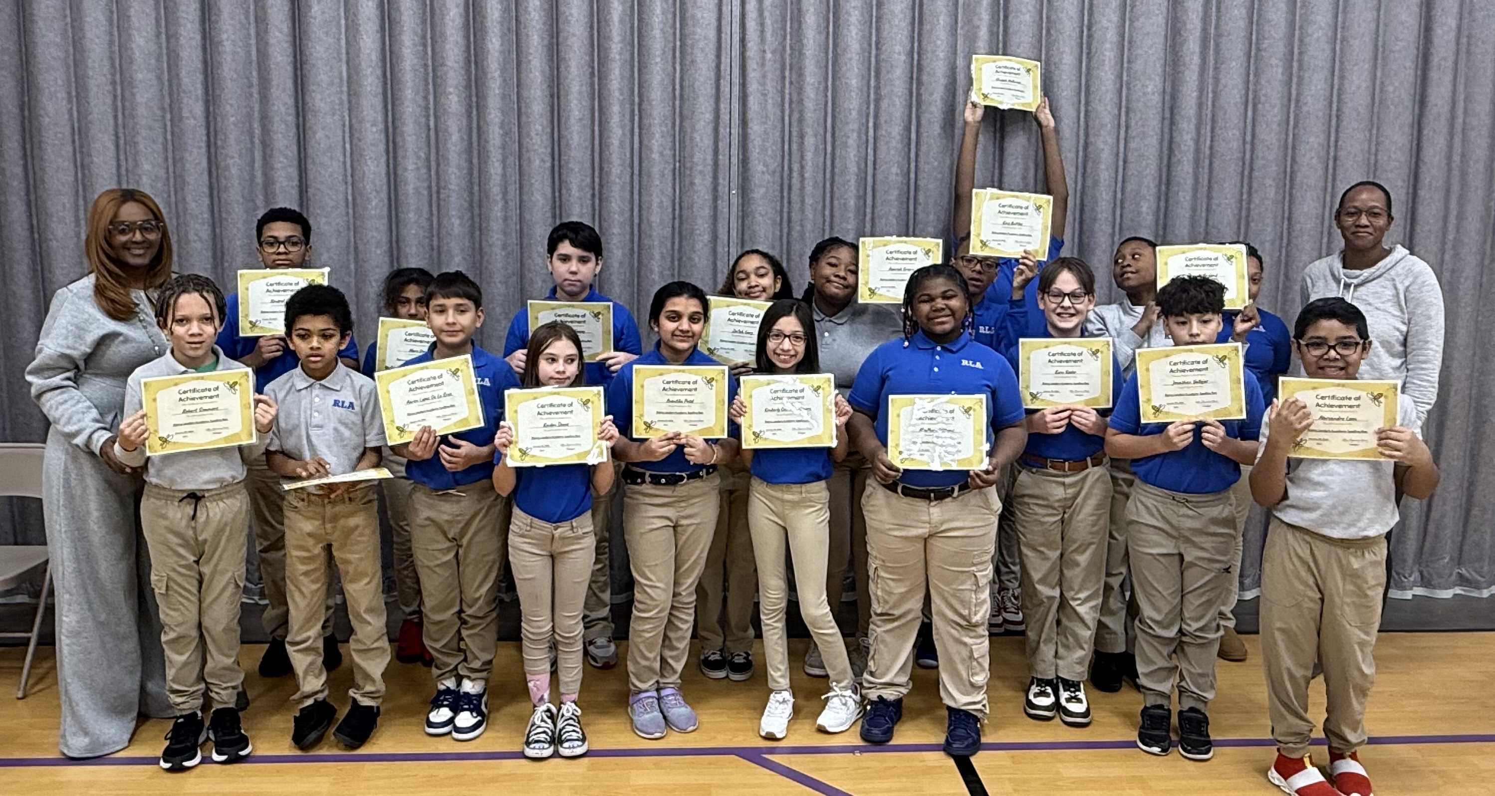 A group of students stand holding certificates of academic achievement
