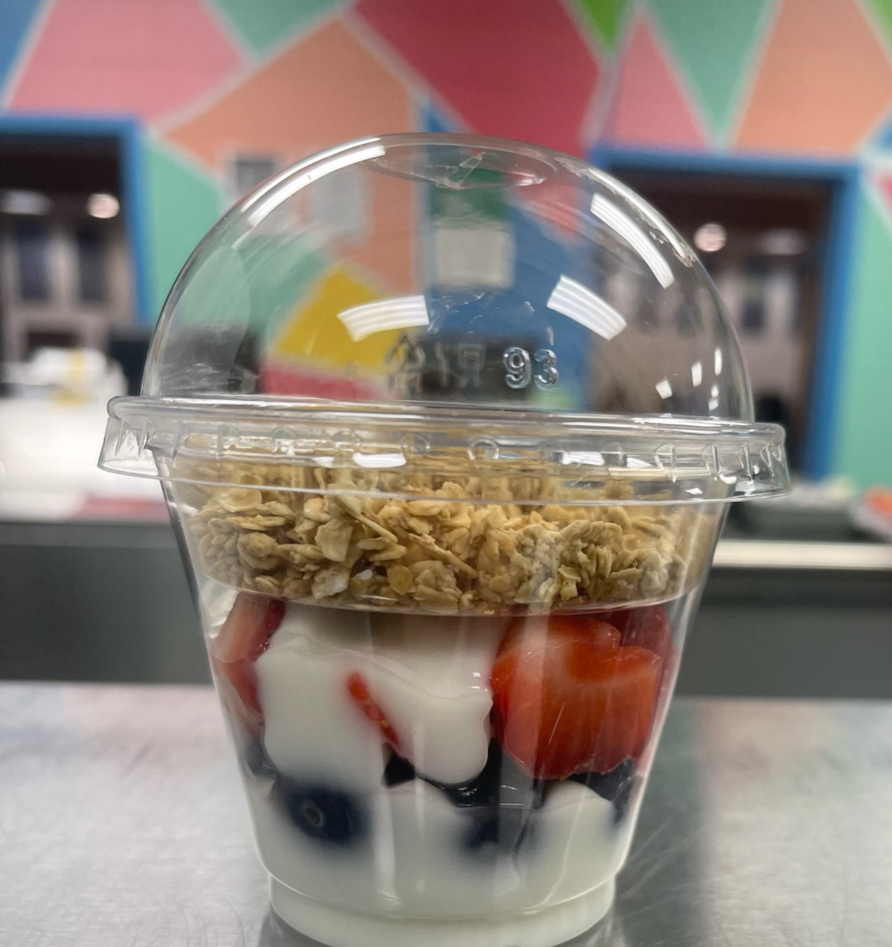 A plastic container filled with yogurt and fruit