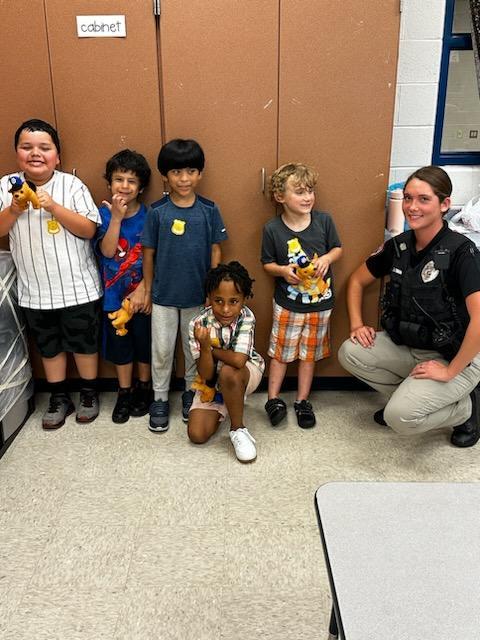 A police officer smiling with a group of children for a photo.