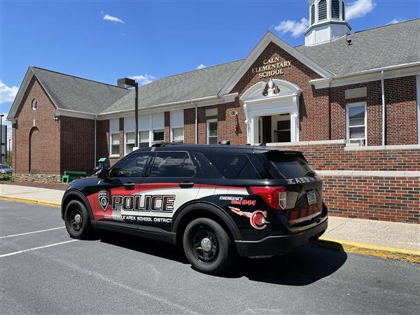 A police car parked in front of a brick building.