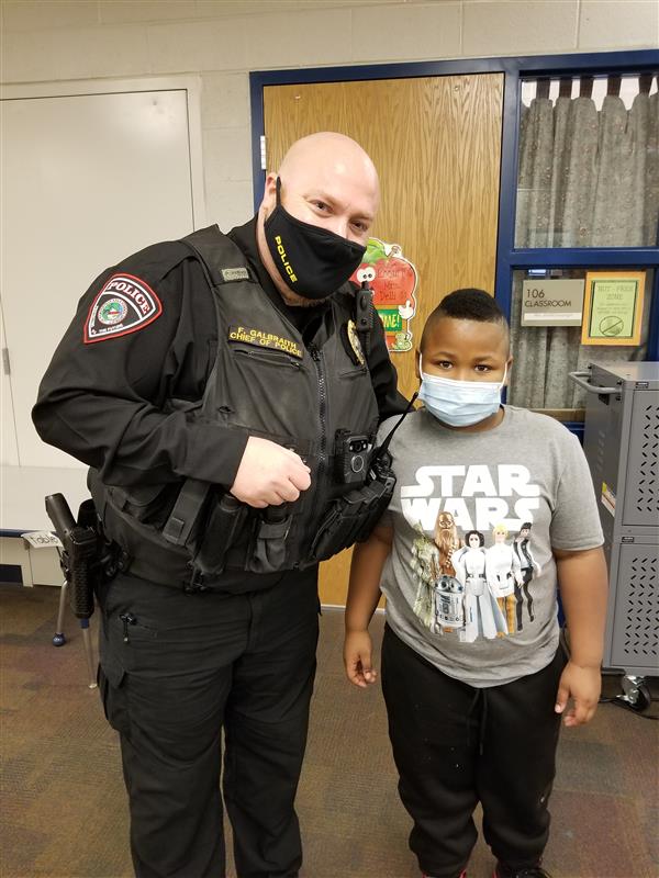 Police officer standing next to boy in mask.