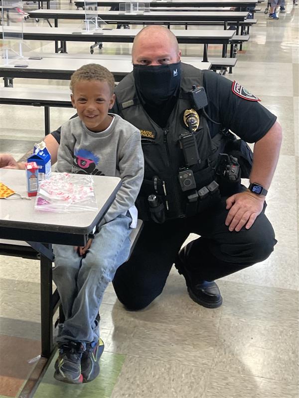 A police officer sitting at a table with a child, engaging in a friendly conversation.