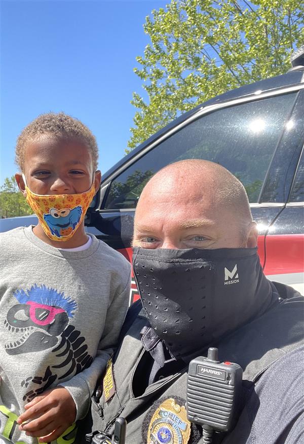 A police officer and a child wearing face masks, standing together.