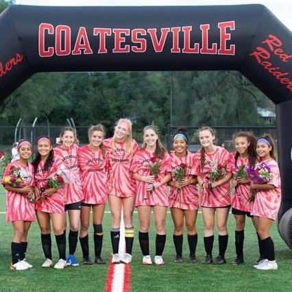 The girls soccer team gathers under an inflatable arch for a group photo.