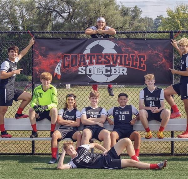 Group of boys in soccer uniforms posing for team photo on field.