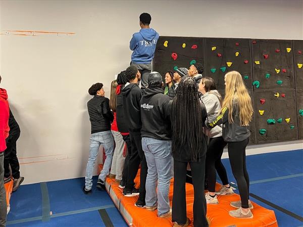 Several individuals climbing a rock wall at an indoor gym.