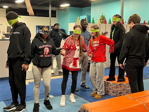 Several individuals wearing blindfolds in a fitness center.