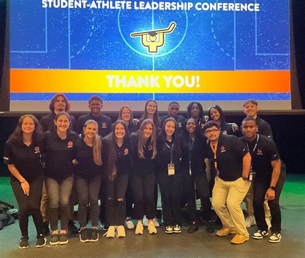 A group of student athletes attending a leadership conference, engaging in discussions and team-building activities.