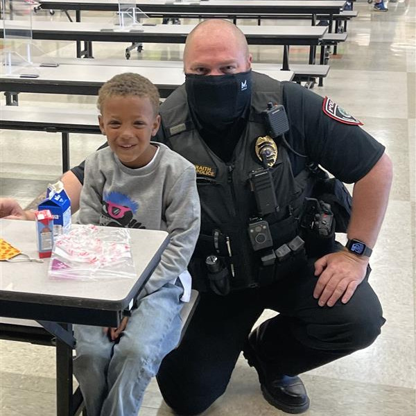 A police officer sitting at a table with a child, engaging in a friendly conversation.