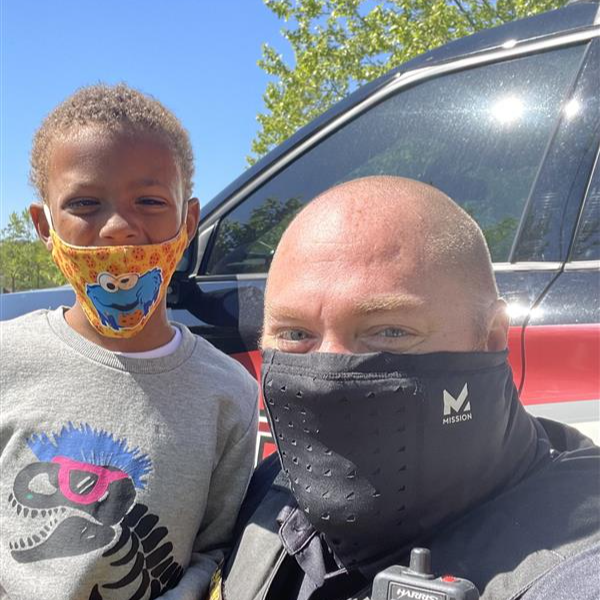 A police officer and a child wearing face masks, standing together.