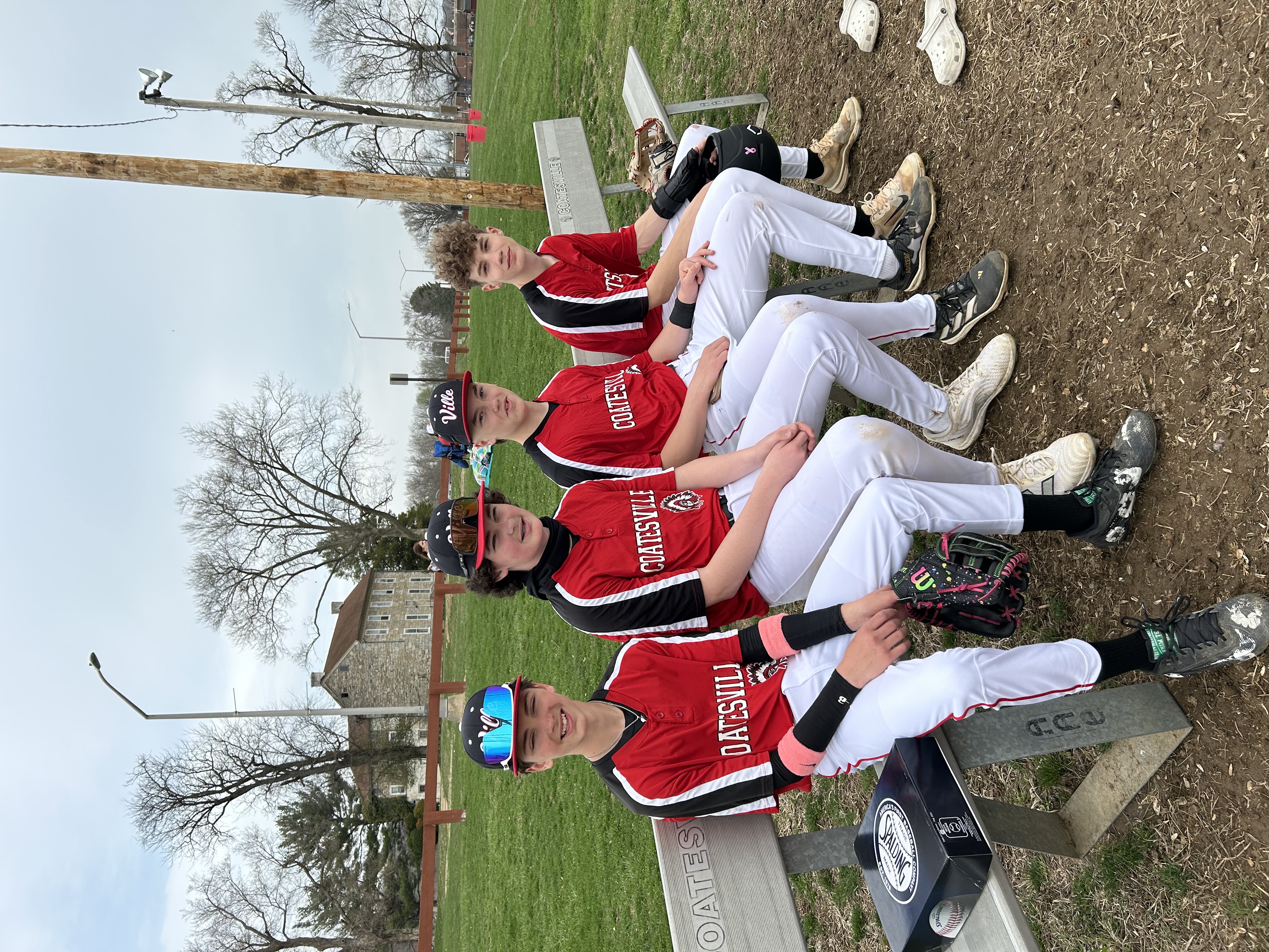 four boys in baseball uniforms sitting on a bench
