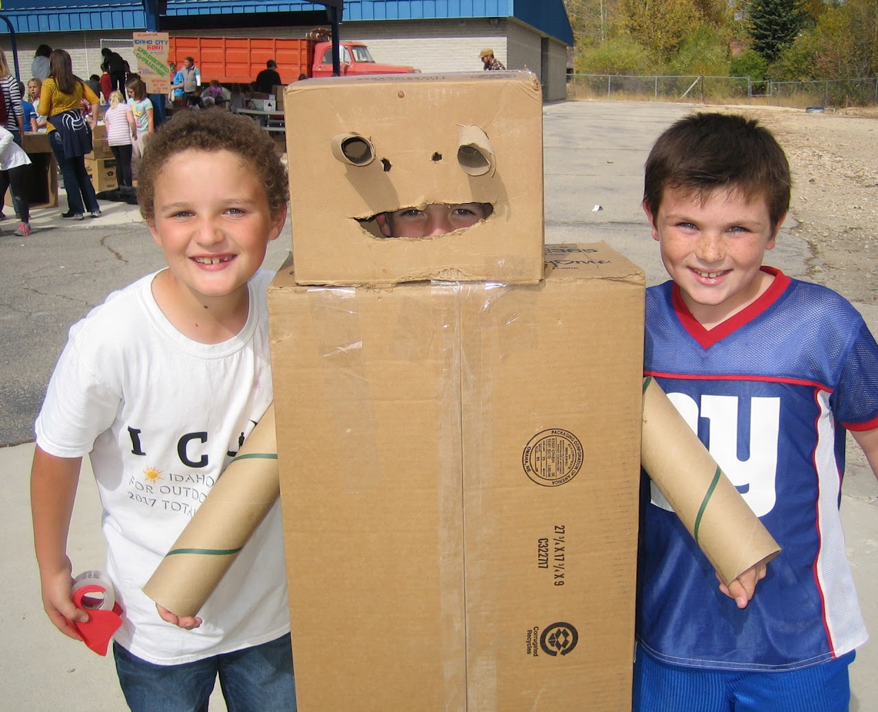kids with cardboard robot smiling looking at camera