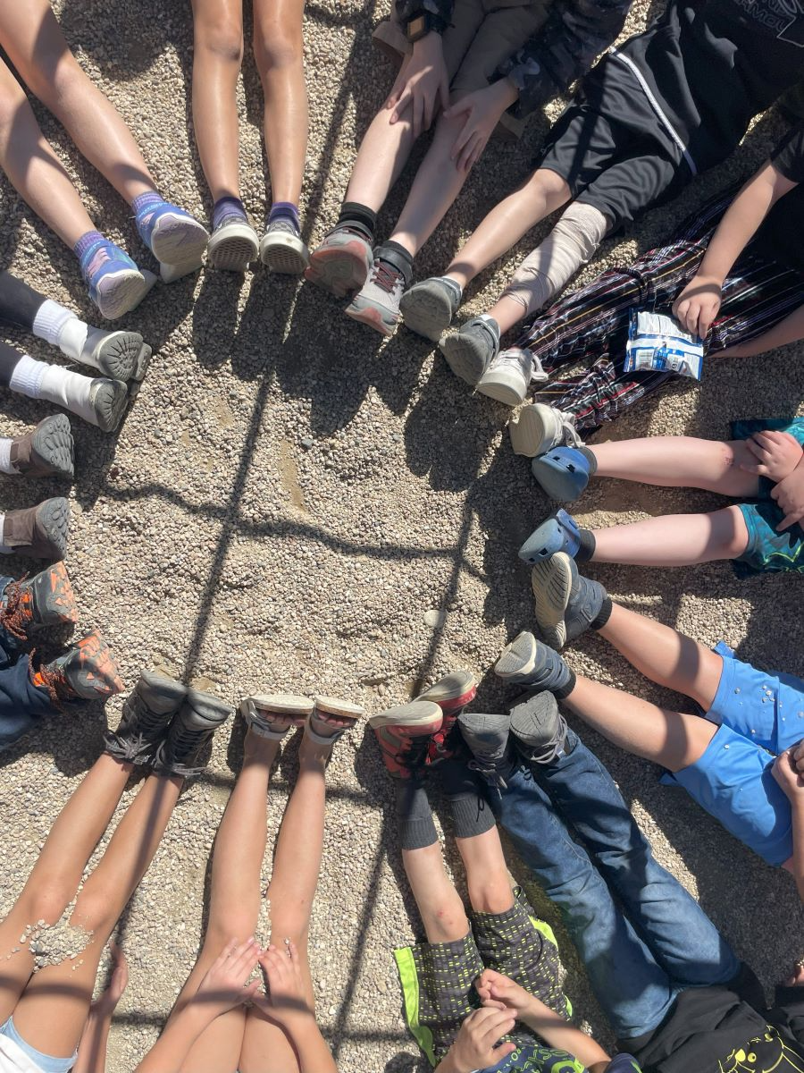 students sitting on the ground making a circle with their feet