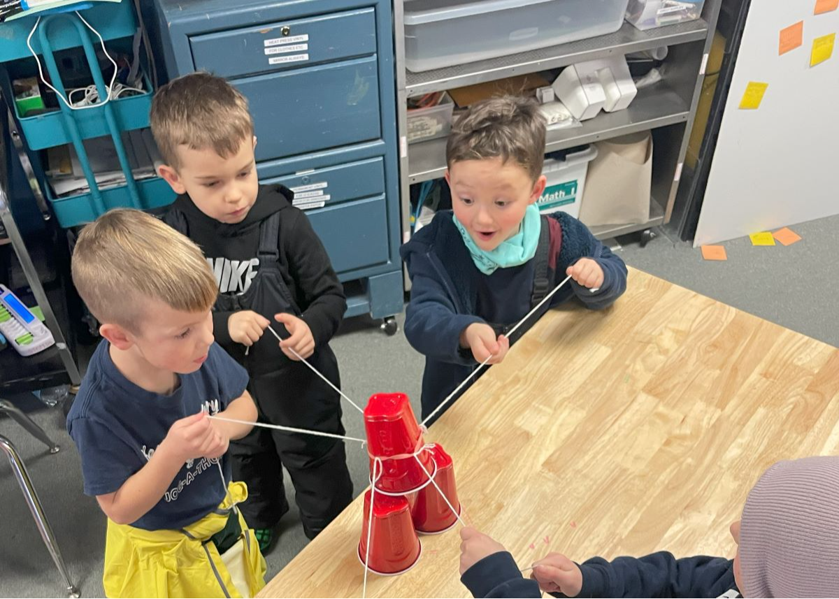 kids holding strings attached to a plastic cup